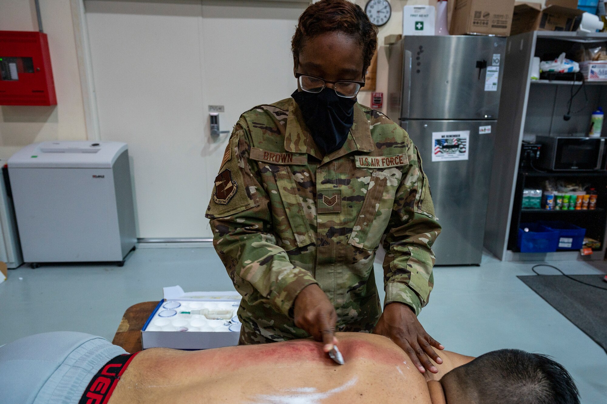 Scraping therapy is applied to an Airman's back