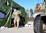 Spc. Madalyn Stella, combat medic, 197th Field Artillery Brigade, New Hampshire Army National Guard, emerges from a medical tent with a COVID-19 vaccine for a waiting patient Dec. 29, 2020, in Exeter, N.H. Stella is one of 11 members of the Guard assigned to the vaccination station, one of 13 across the state.