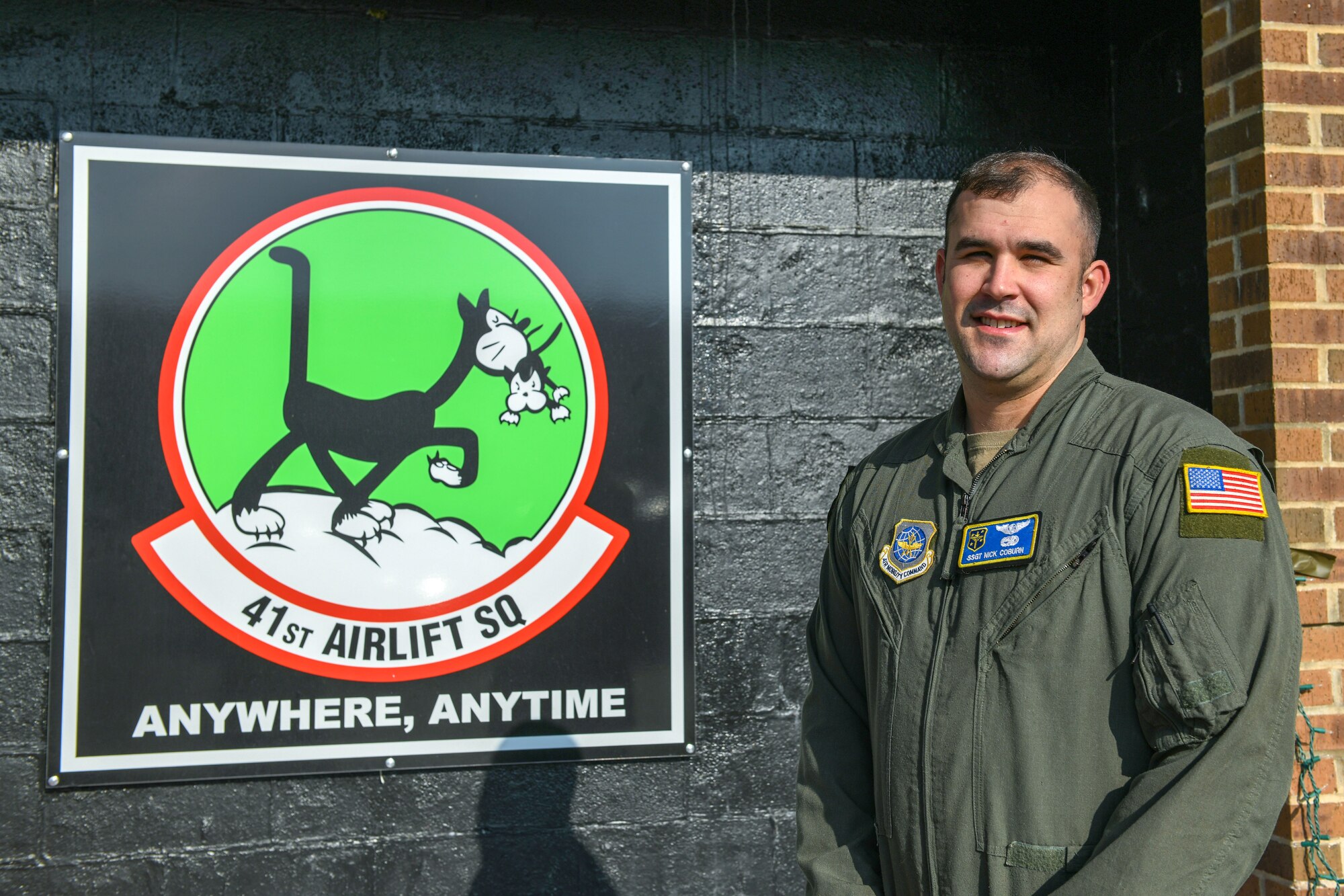A man stands in uniform in front of a sign.