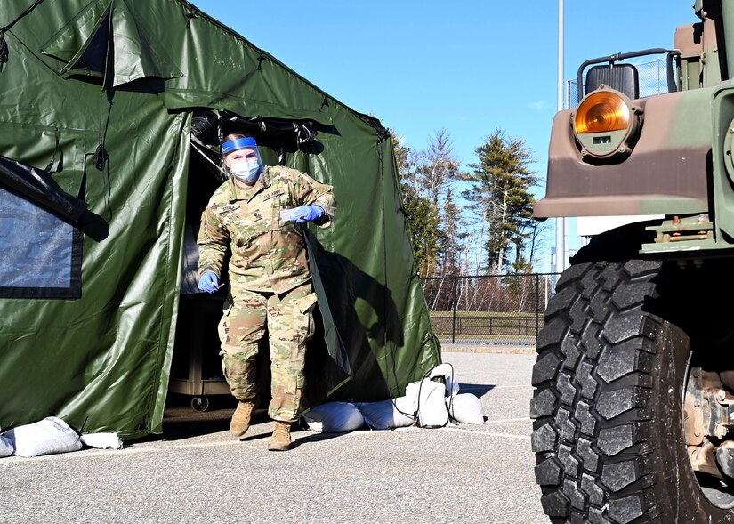 A medic wearing protective gear emerges from a green tent.