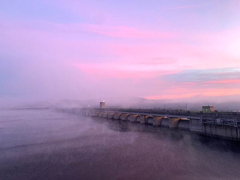 table rock dam shrouded in fog with a multi-colored morning backdrop