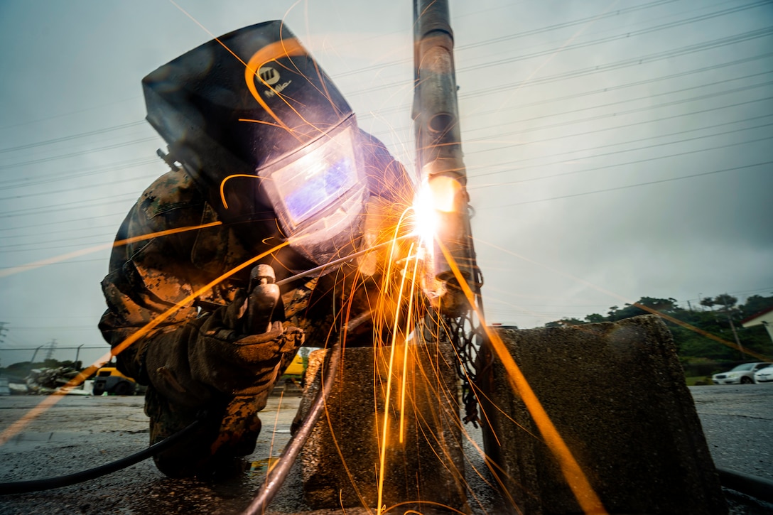 A Marine welds a fence.