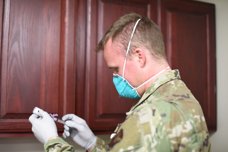 A member of the 341st Missile Wing Medical Group examines a dose of the COVID-19 vaccine.