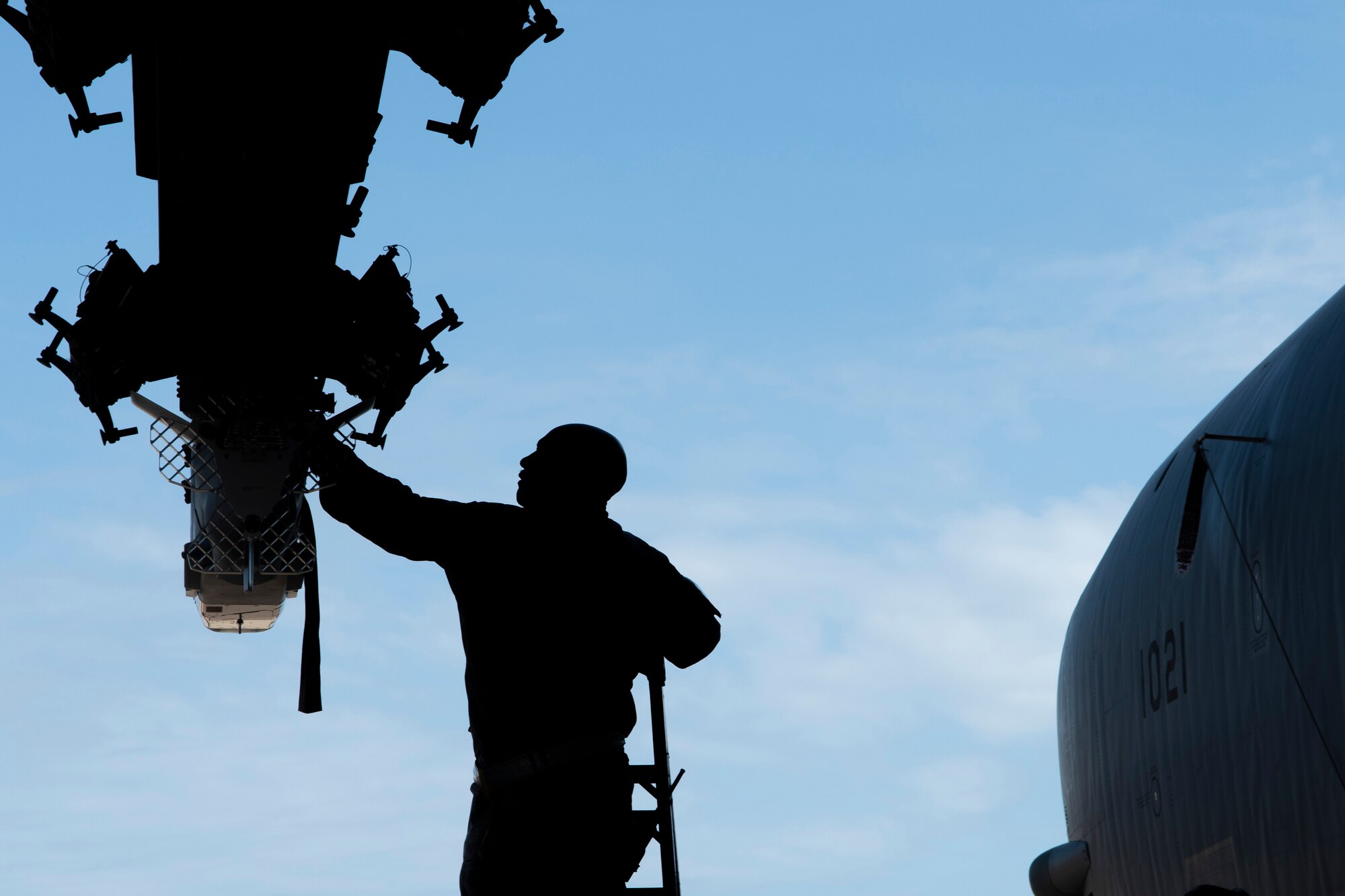 Airman is silhouetted while loading a bomb.