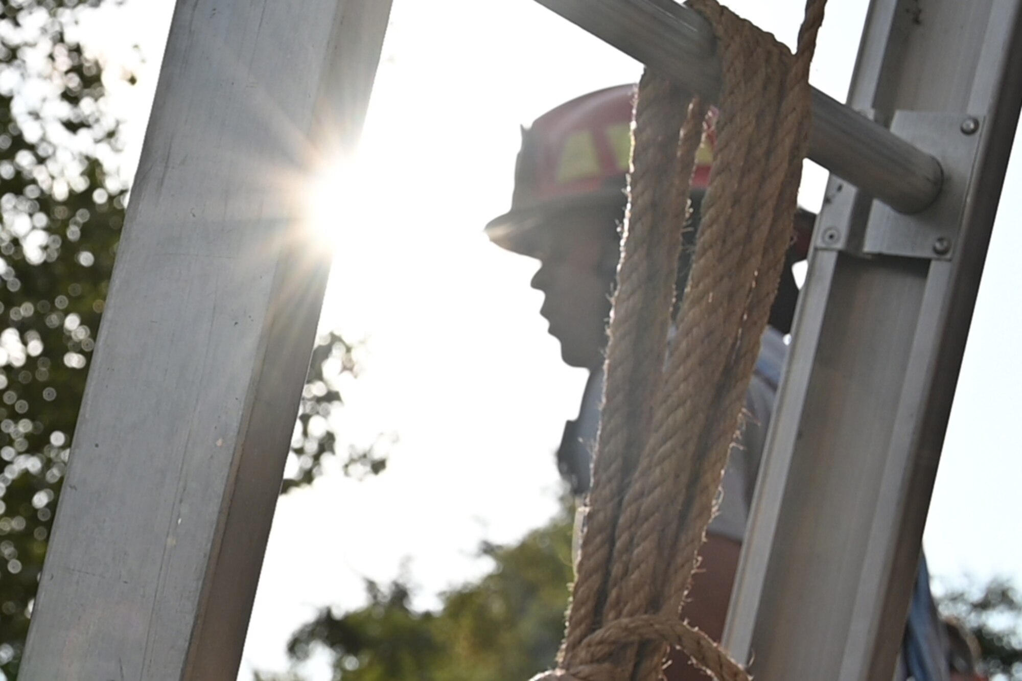 An Airman is framed in the ladder as the sun glares down.