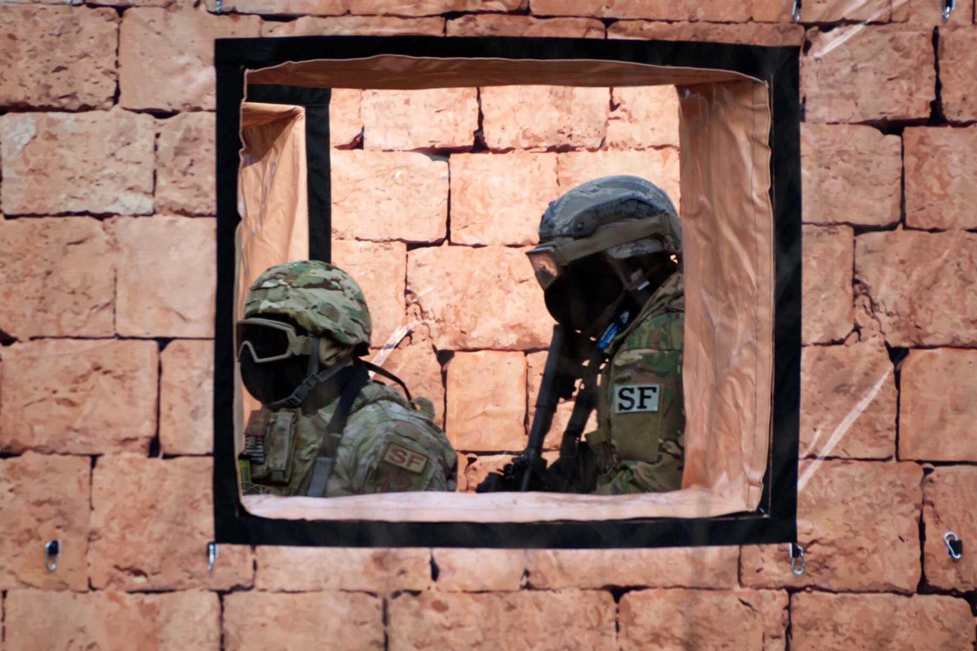 Airmen are framed in the window of an obstacle course.