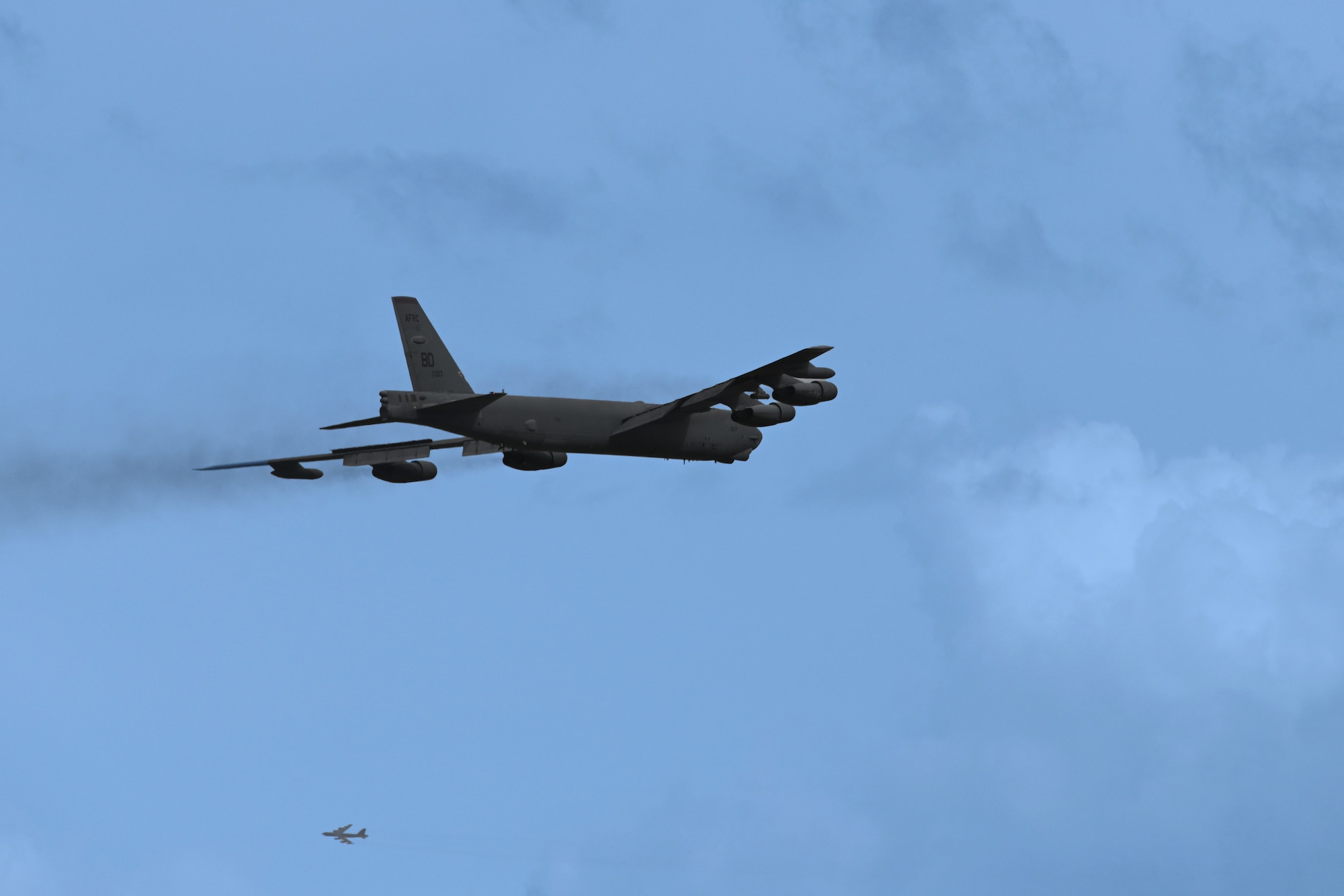 Two B-52's take off into a blue sky.