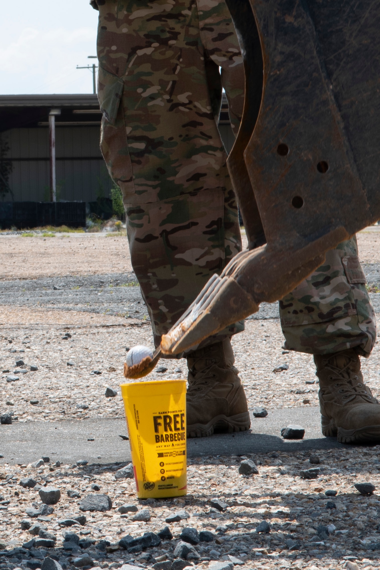 A golfball is dropped from a front in loader into a cup.