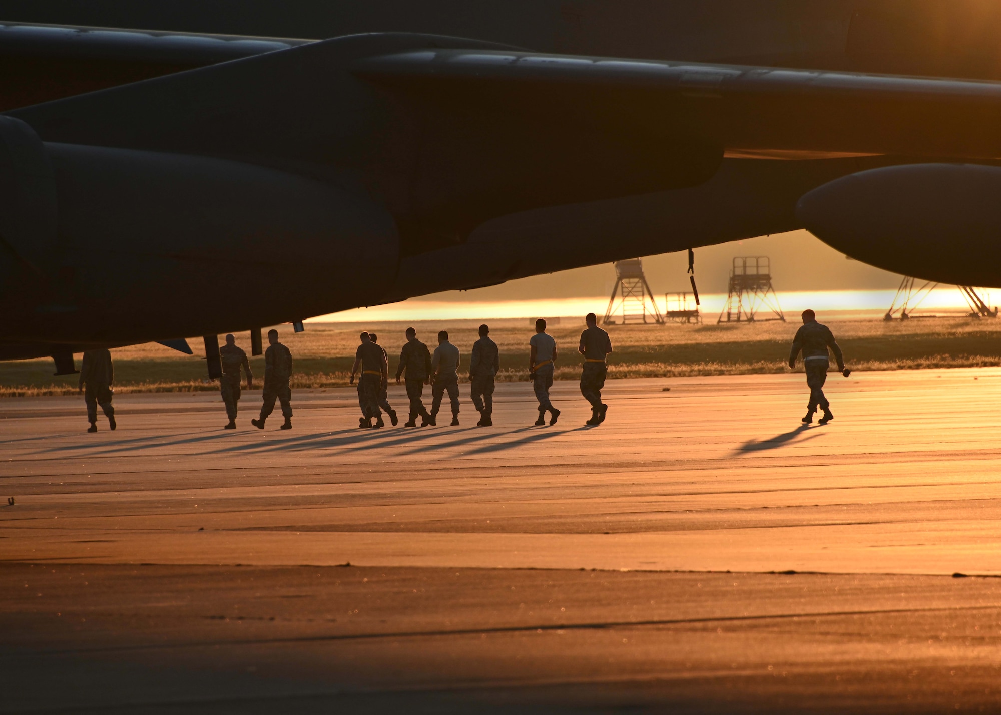 Airmen walk on a flight line.