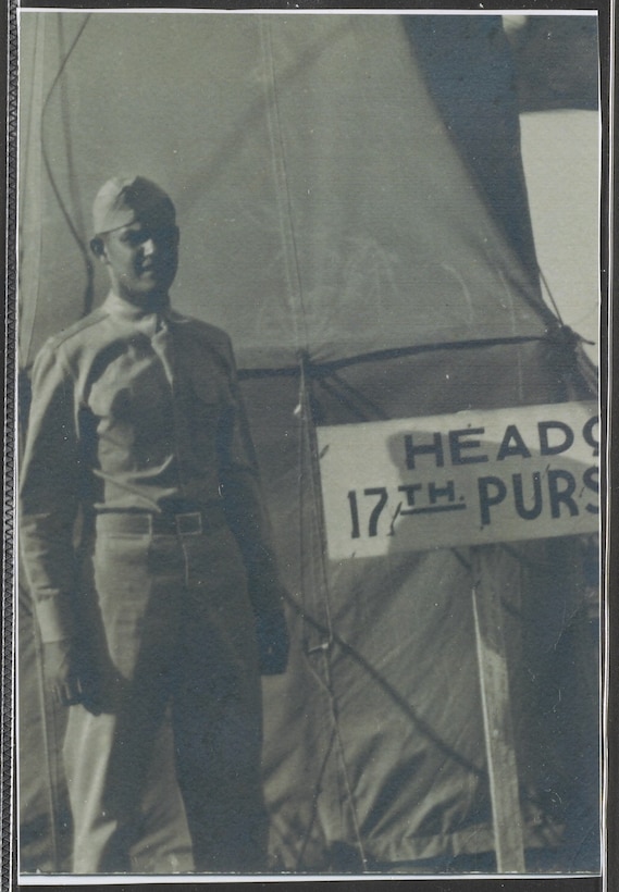 A man in a military uniform stands in front of a tent.