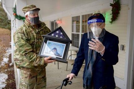 Col. Adam Rice (left), vice wing commander of the 158th Fighter Wing, Vermont Air National Guard, presents a flag flown in the F-35A Lightning II to WWII veteran Lenny Roberge, Vermont’s oldest living veteran, outside his nursing home in South Burlington, Vt., Dec. 22, 2020. In order to honor Roberge, Airmen from the 158th Fighter Wing had a flag flown in an F-35 during a combat training sortie over the mountains of Vermont and New York. (U.S. Air National Guard photo by Senior Master Sgt. Michael Davis)