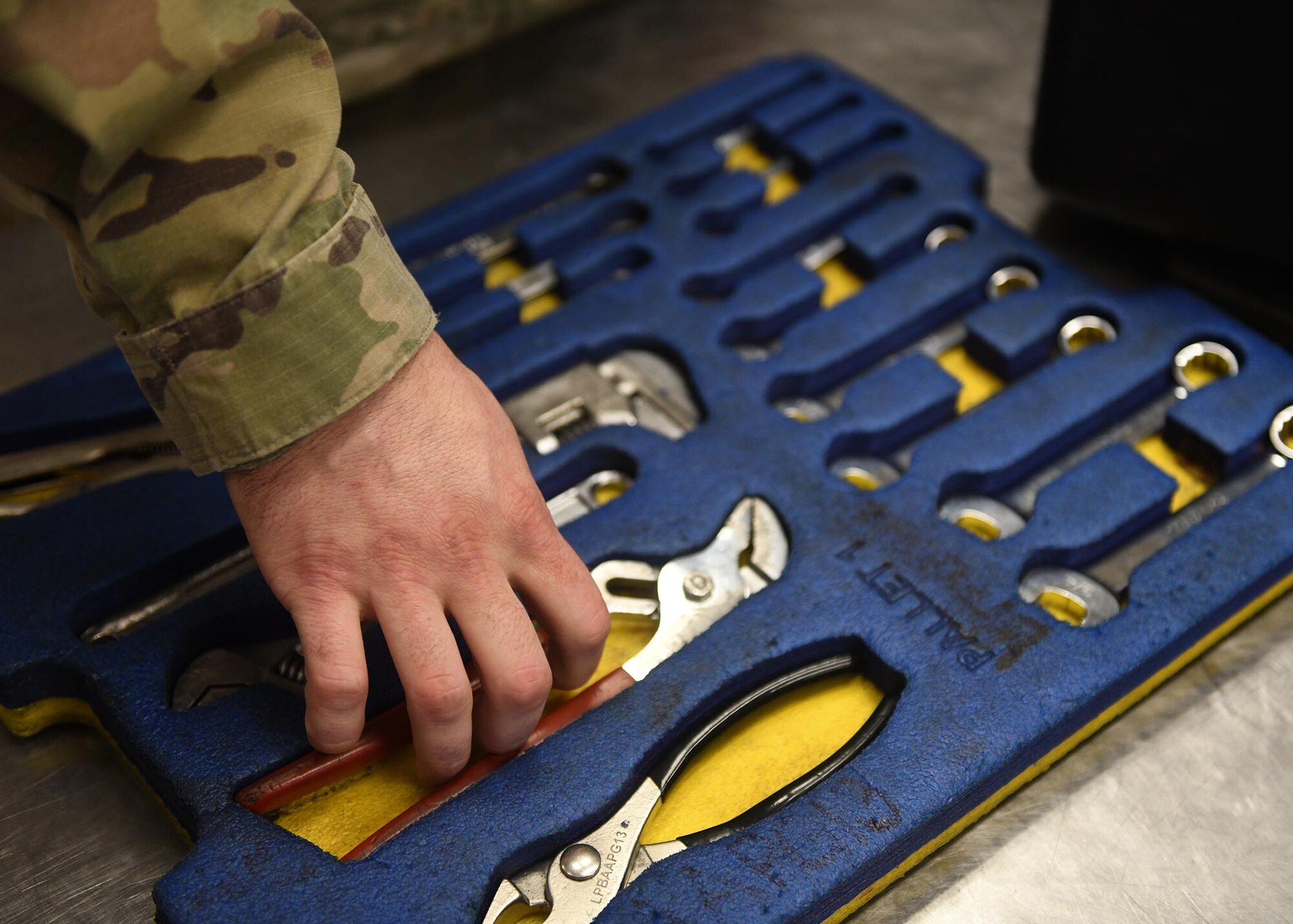 A hand touches a shiny metal tool.