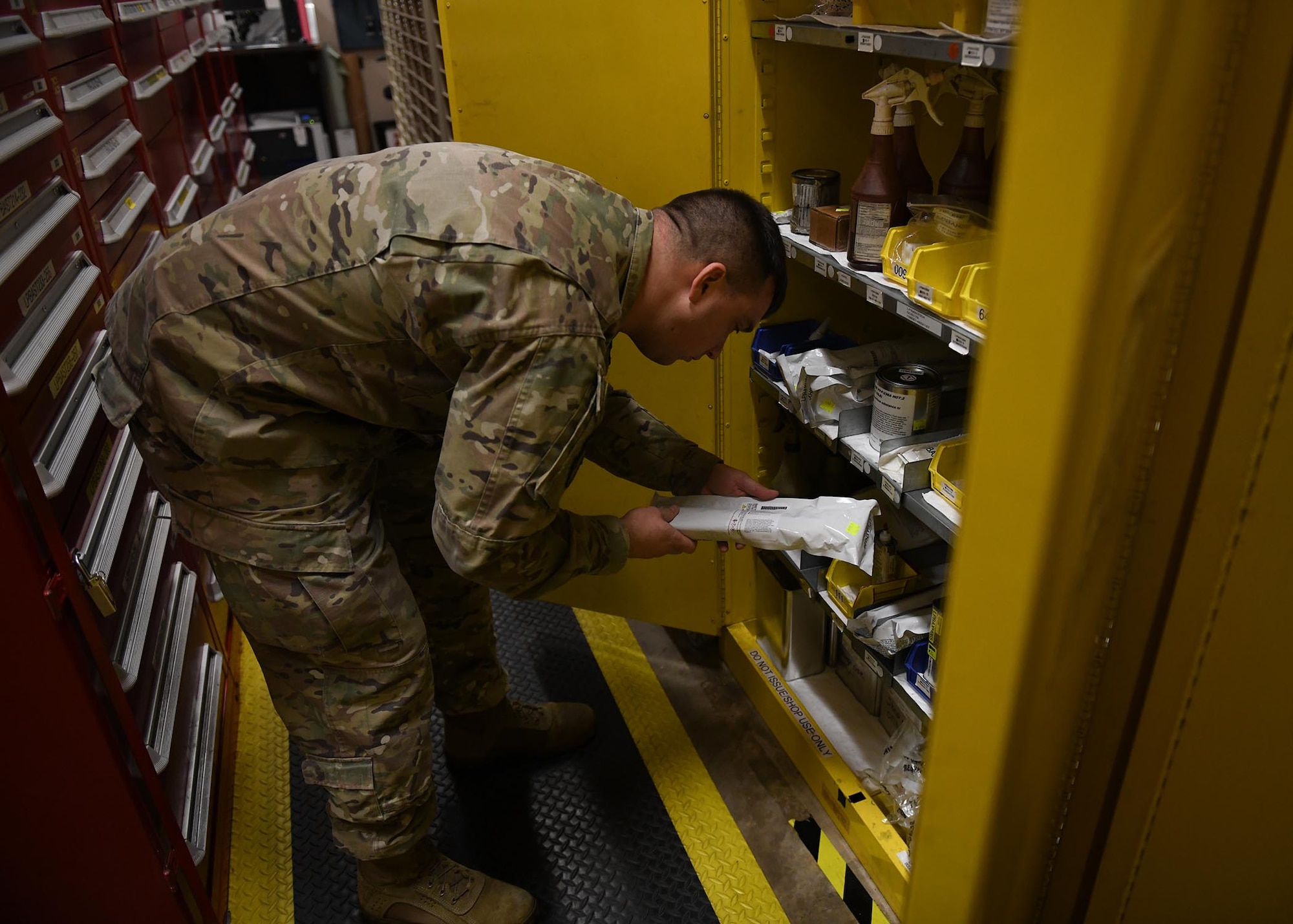 An Airman looks inside a yellow storage container.