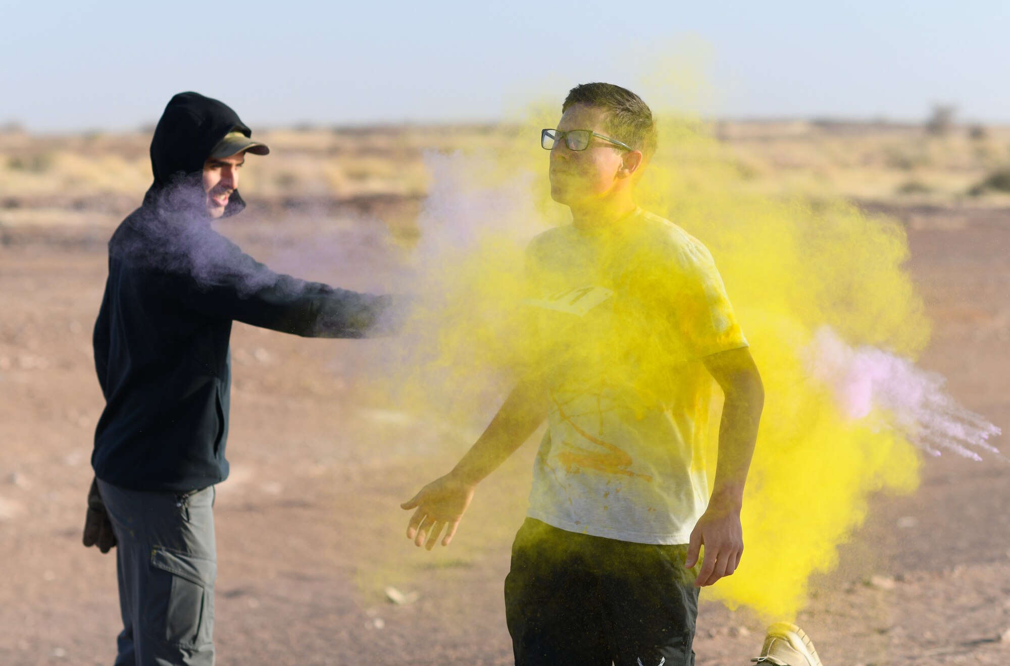A color run participant runs through a gauntlet of paint throwing volunteers at Nigerien Air Base 201, Niger, Feb. 2, 2020. More than 30 runners and volunteers participated in the event. (U.S. Air Force photo by Tech. Sgt. Alex Fox Echols III)
