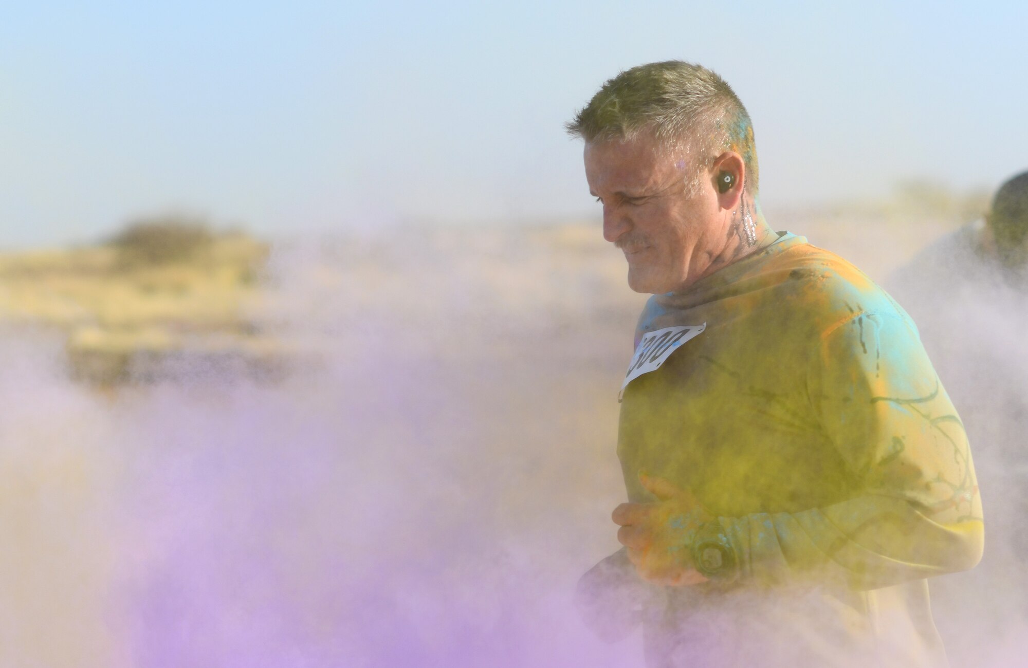 A color run participant runs through a gauntlet of paint throwing volunteers at Nigerien Air Base 201, Niger, Feb. 2, 2020. More than 30 runners and volunteers participated in the event. (U.S. Air Force photo by Tech. Sgt. Alex Fox Echols III)