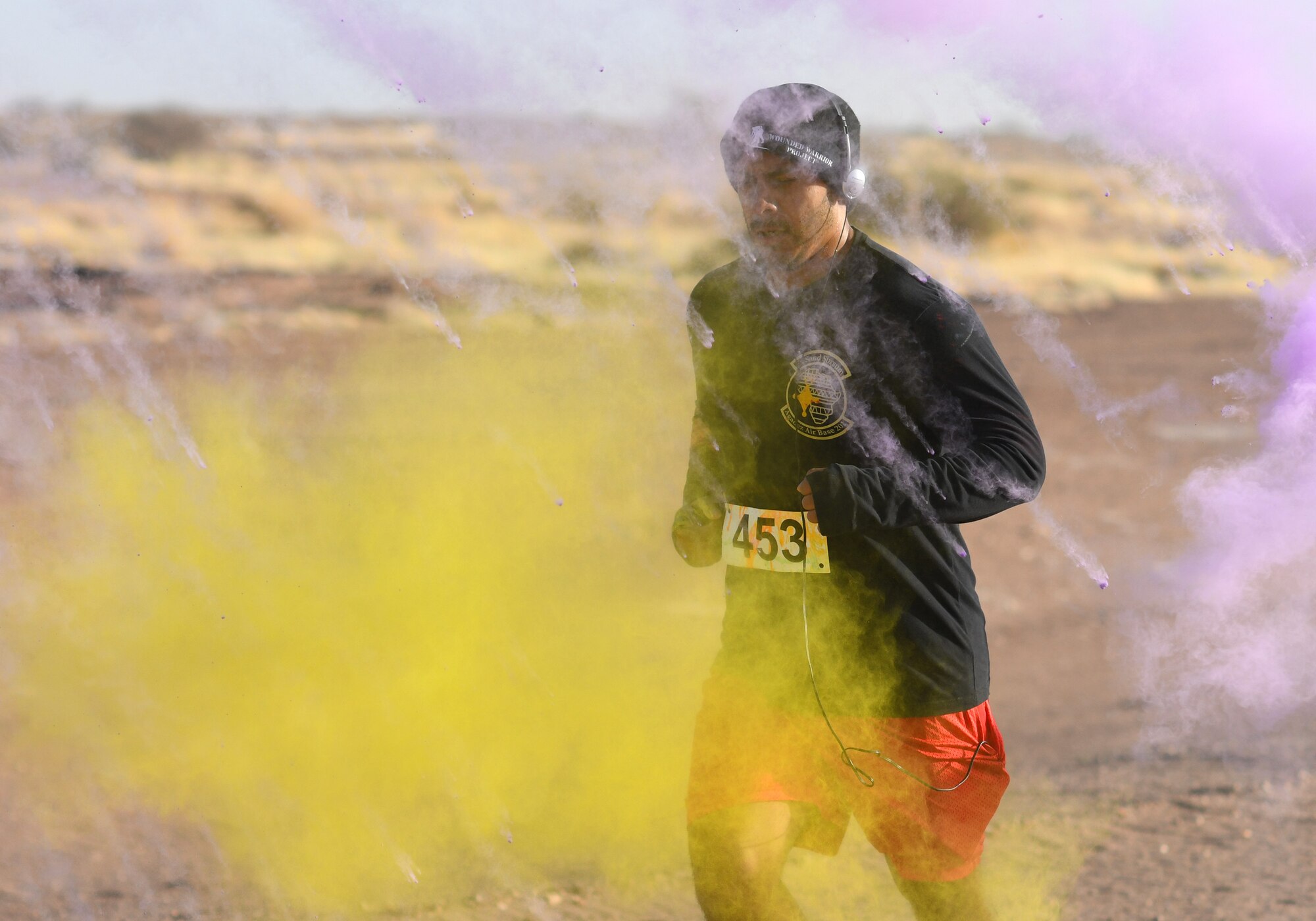 A color run participant runs through a gauntlet of paint throwing volunteers at Nigerien Air Base 201, Niger, Feb. 2, 2020. More than 30 runners and volunteers participated in the event. (U.S. Air Force photo by Tech. Sgt. Alex Fox Echols III)