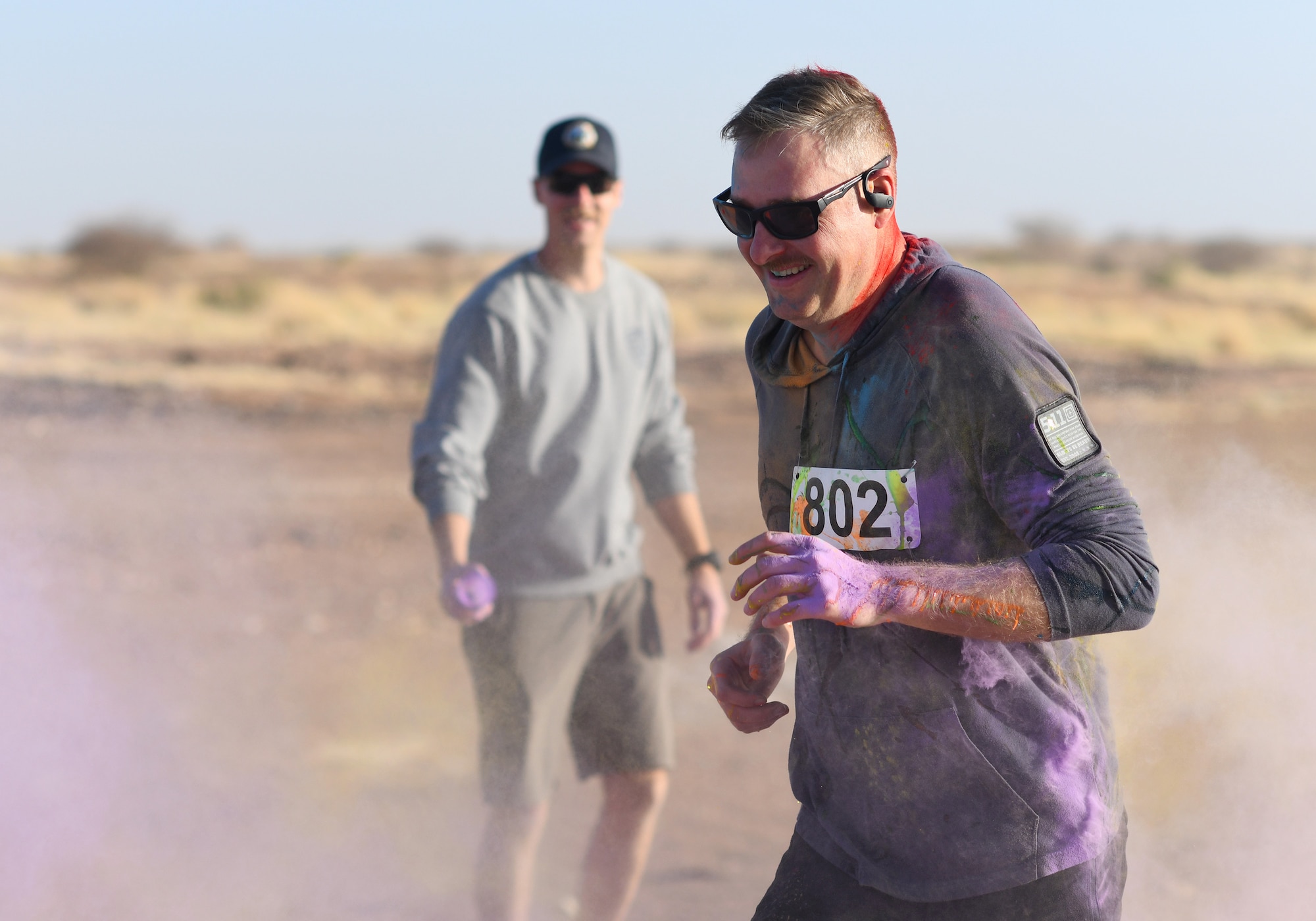 A color run participant runs through a gauntlet of paint throwing volunteers at Nigerien Air Base 201, Niger, Feb. 2, 2020. More than 30 runners and volunteers participated in the event. (U.S. Air Force photo by Tech. Sgt. Alex Fox Echols III)