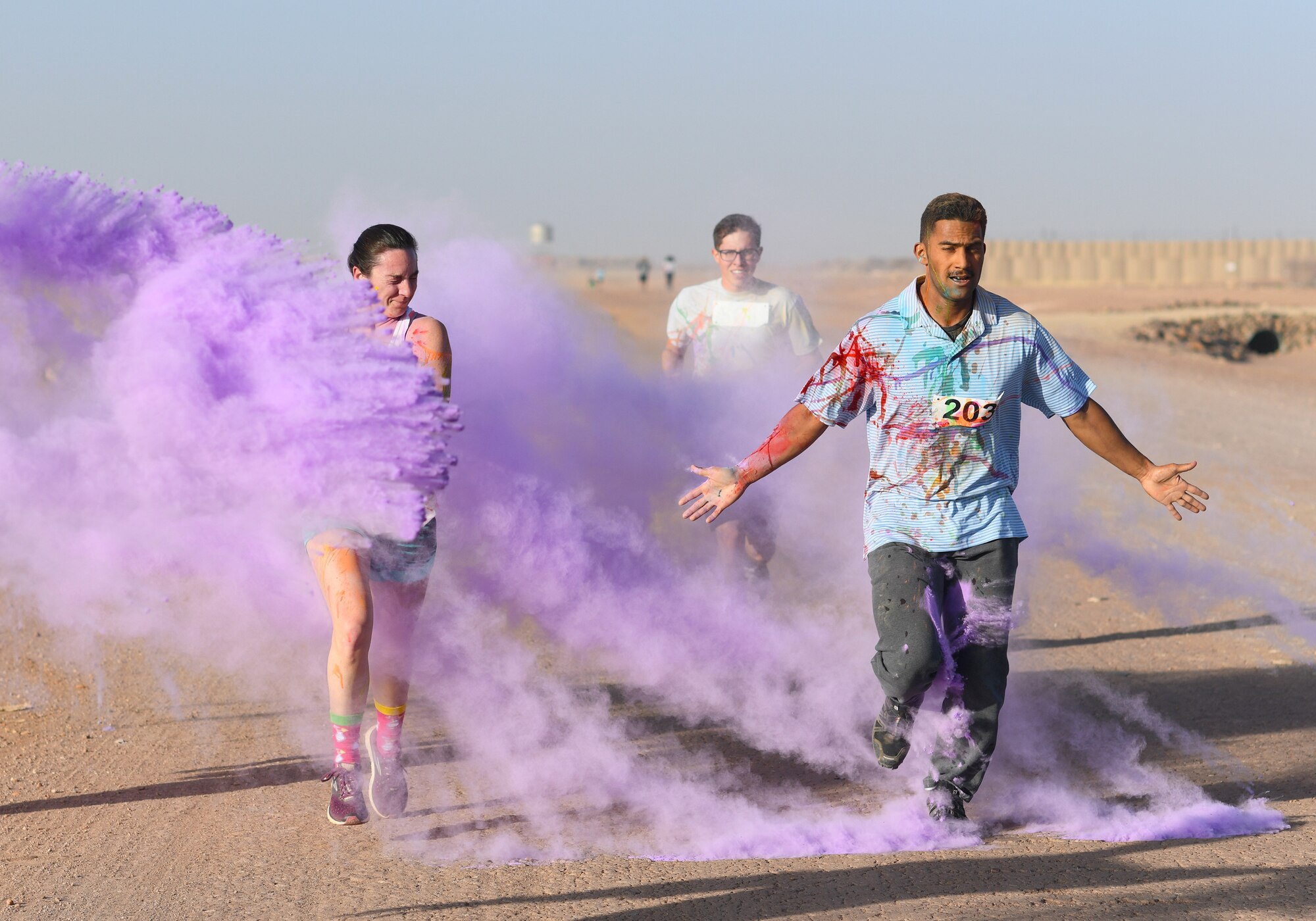 Color run participants run through a gauntlet of paint throwing volunteers at Nigerien Air Base 201, Niger, Feb. 2, 2020. More than 30 runners and volunteers participated in the event. (U.S. Air Force photo by Tech. Sgt. Alex Fox Echols III)