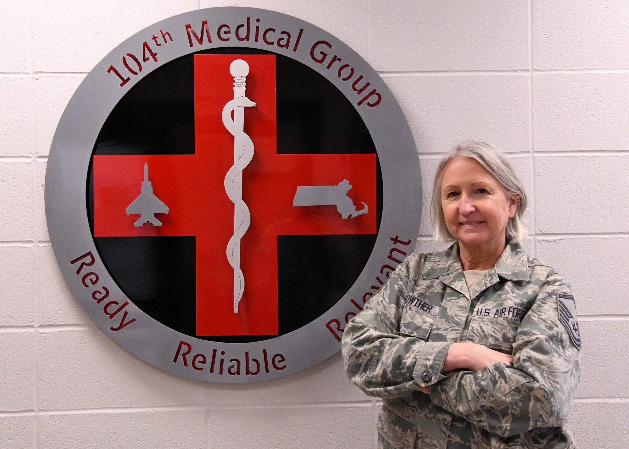 U.S. Air Force Master Sgt. Terrylee Lois Crowther, a dental technician assigned to the 104th Fighter Wing, Massachusetts Air National Guard, poses for a photo in front of the 104th Medical Group crest at Barnes Air National Guard Base, Mass., Feb. 2, 2020. Crowther is the NCOIC of dental at the 104th FW and is nearing her retirement after 40 years of military service. (U.S. Air National Guard photo by Airman Camille Lienau)