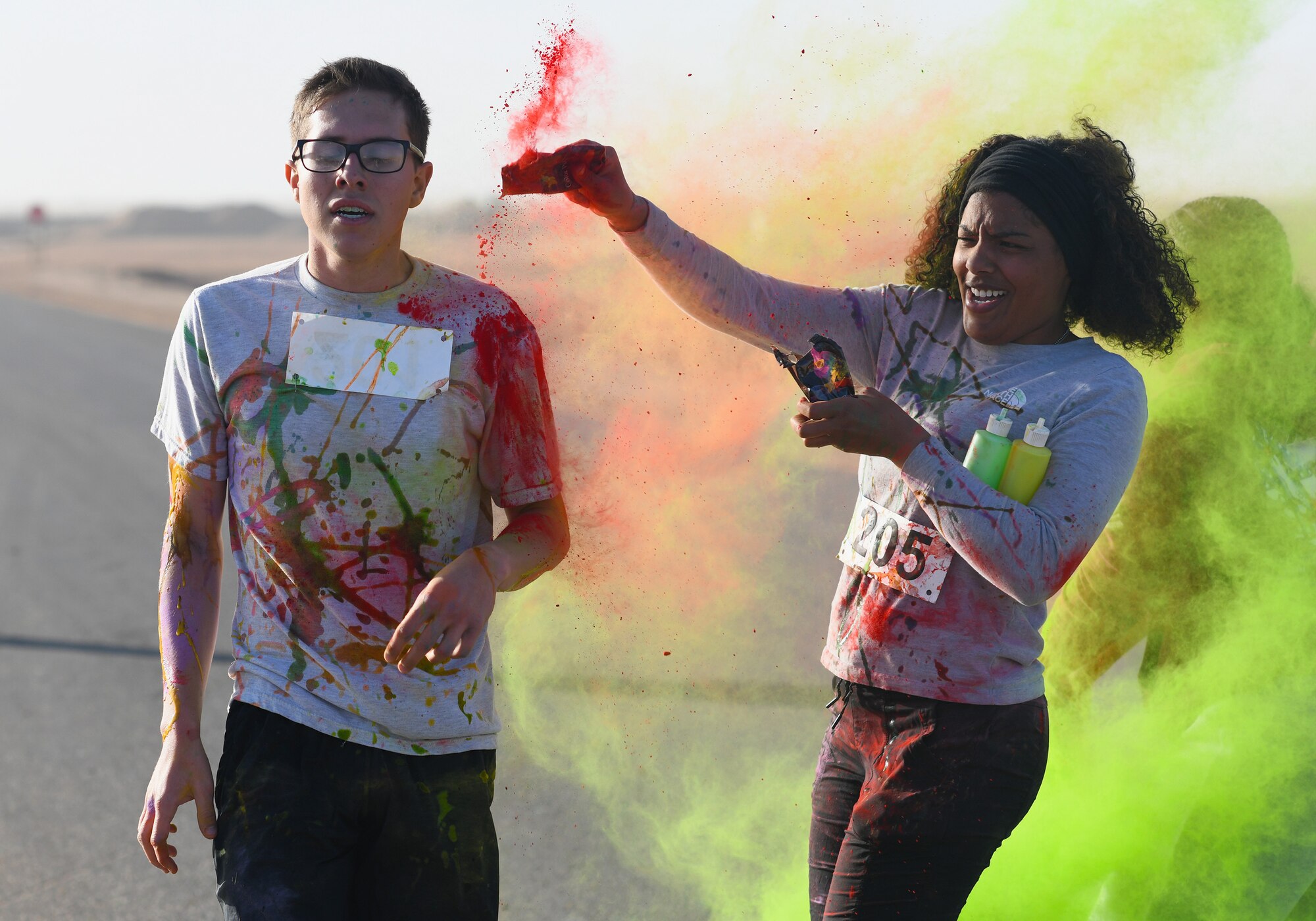 A color run participant runs through a gauntlet of paint throwing volunteers at Nigerien Air Base 201, Niger, Feb. 2, 2020. More than 30 runners and volunteers participated in the event. (U.S. Air Force photo by Tech. Sgt. Alex Fox Echols III)