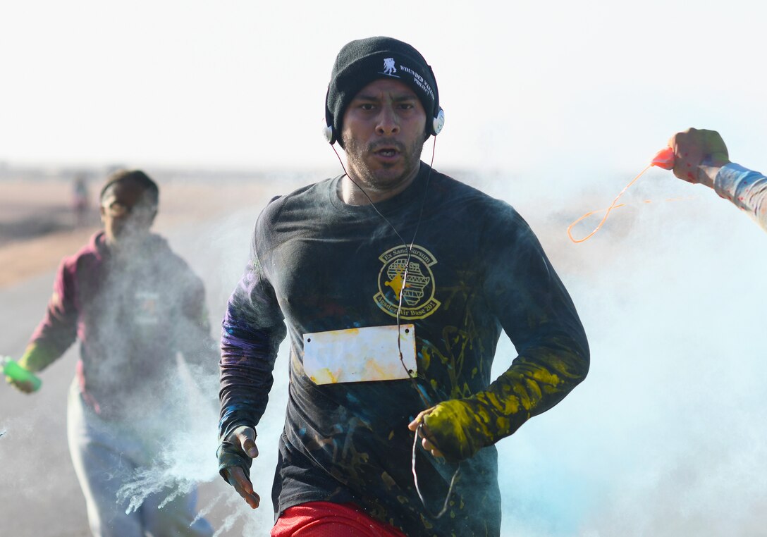 A color run participant runs through a gauntlet of paint throwing volunteers at Nigerien Air Base 201, Niger, Feb. 2, 2020. More than 30 runners and volunteers participated in the event. (U.S. Air Force photo by Tech. Sgt. Alex Fox Echols III)