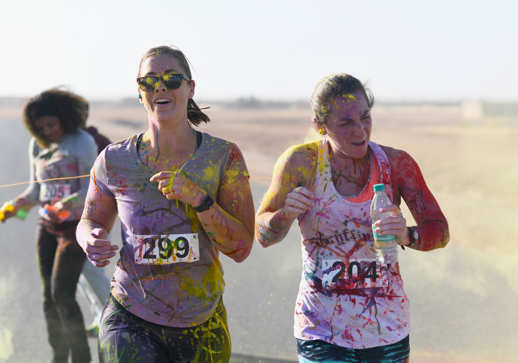 Color run participants run through a gauntlet of paint throwing volunteers at Nigerien Air Base 201, Niger, Feb. 2, 2020. More than 30 runners and volunteers participated in the event. (U.S. Air Force photo by Tech. Sgt. Alex Fox Echols III)