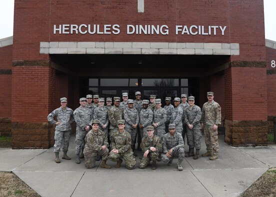 Airmen pose for a photo in front of a dining facility.