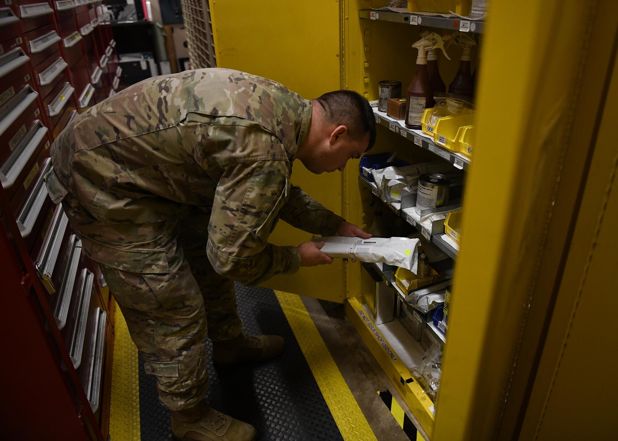 An Airman looks inside a yellow storage container.