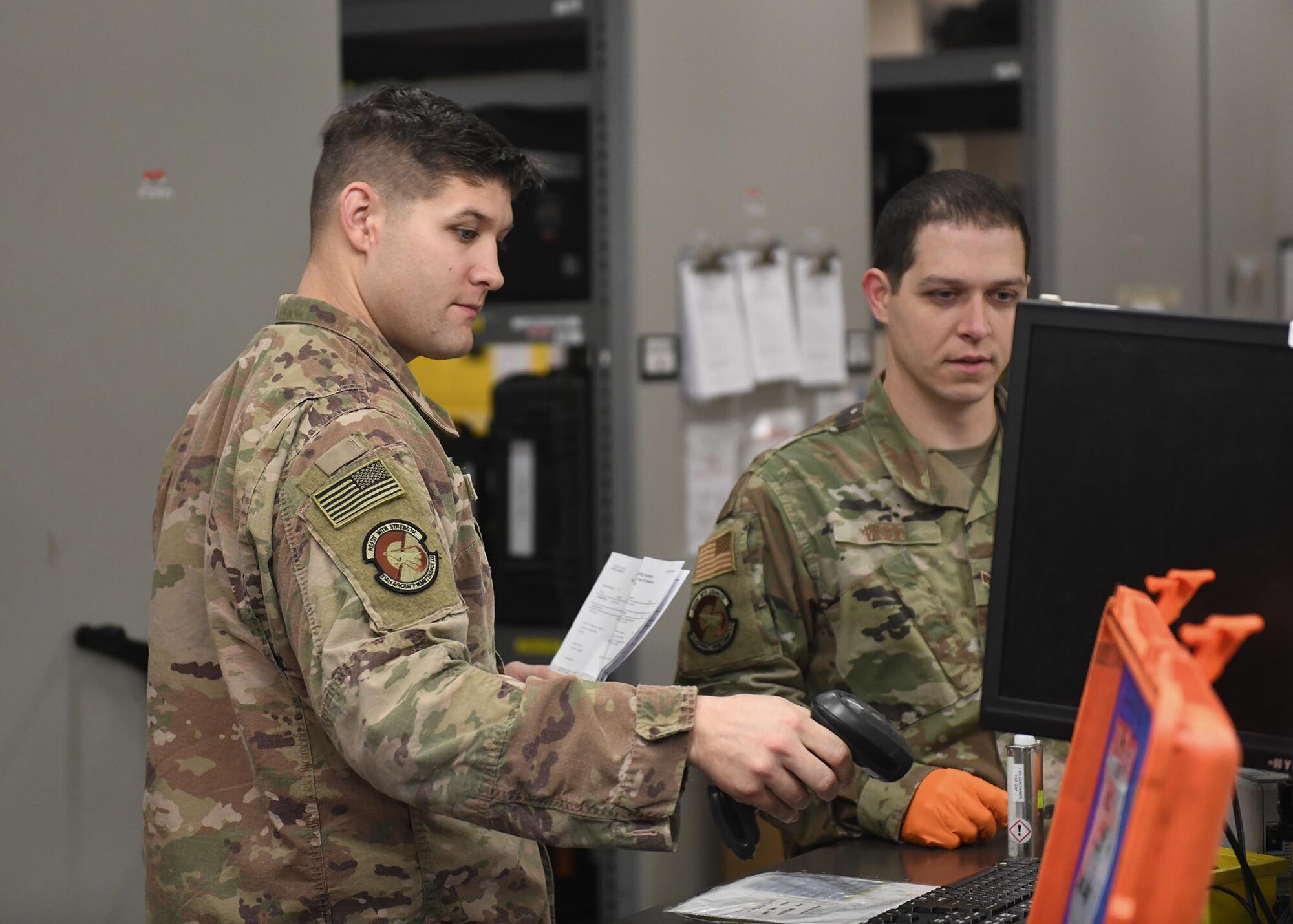 Two Airmen look at a computer screen.