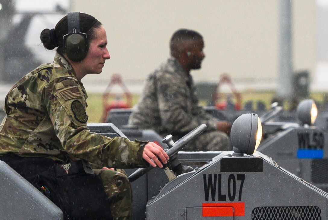 An airman drives a machine wearing a uniform and headphones.