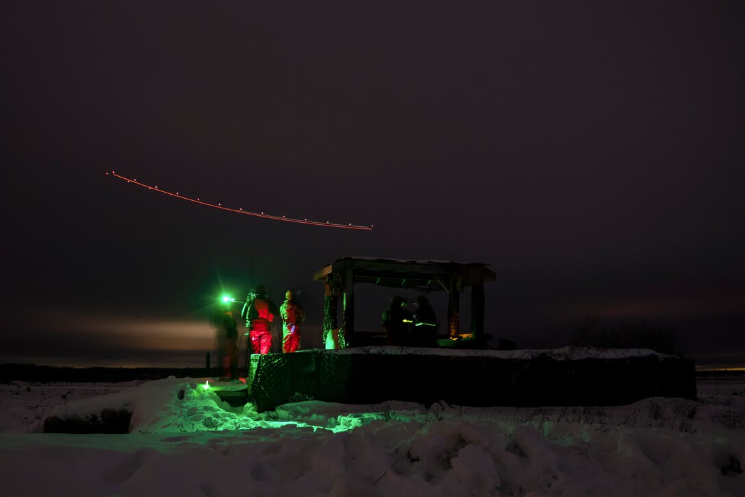Airman watch a simulated airstrike at night.
