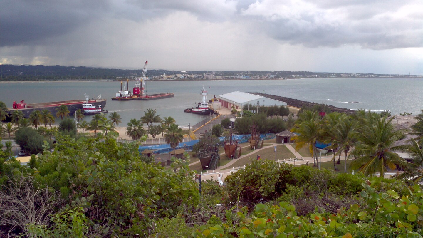 Dredging machines in the water with green vegetation on the bottom of the photo