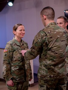 Sgt. Maj. Mary Groy’s brother, Sgt. 1st Class Larry Groy, places her new rank on her uniform during the promotion ceremony Jan. 31 at the Illinois State Military Museum.