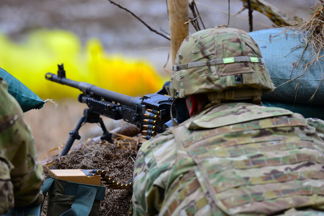 A paratrooper shoots a machine gun.