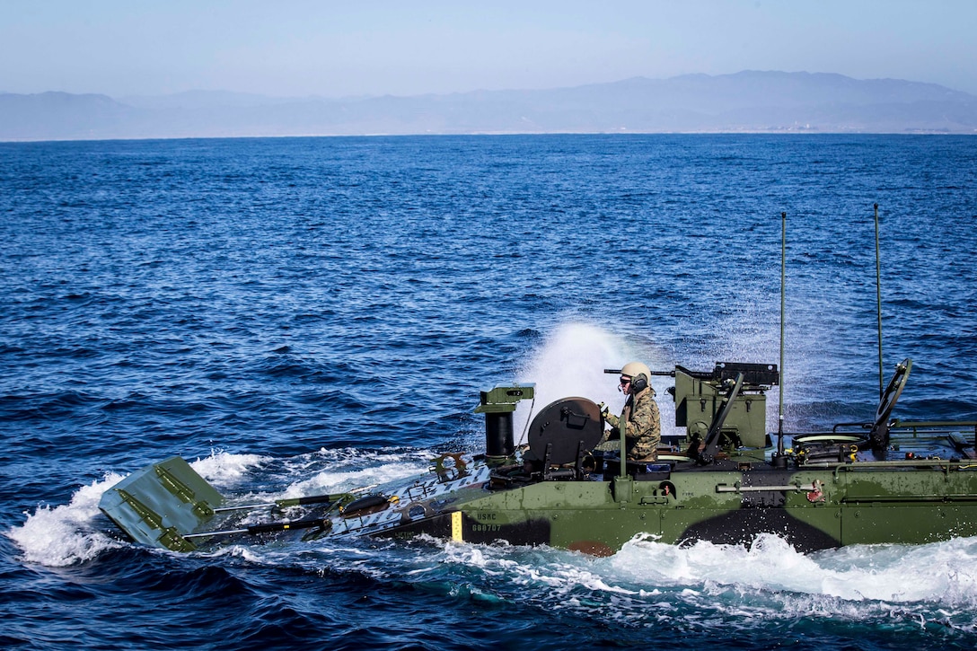 A Marine drives an amphibious combat vehicle through waters.