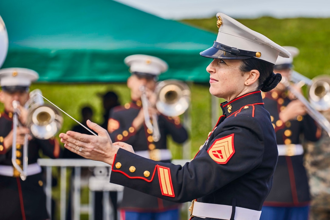 A Marine uses a baton to direct a band.