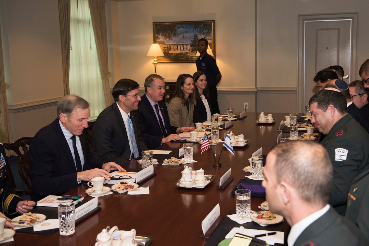 Defense Secretary Dr. Mark T. Esper sits at a rectangular table with other people dressed in suits.