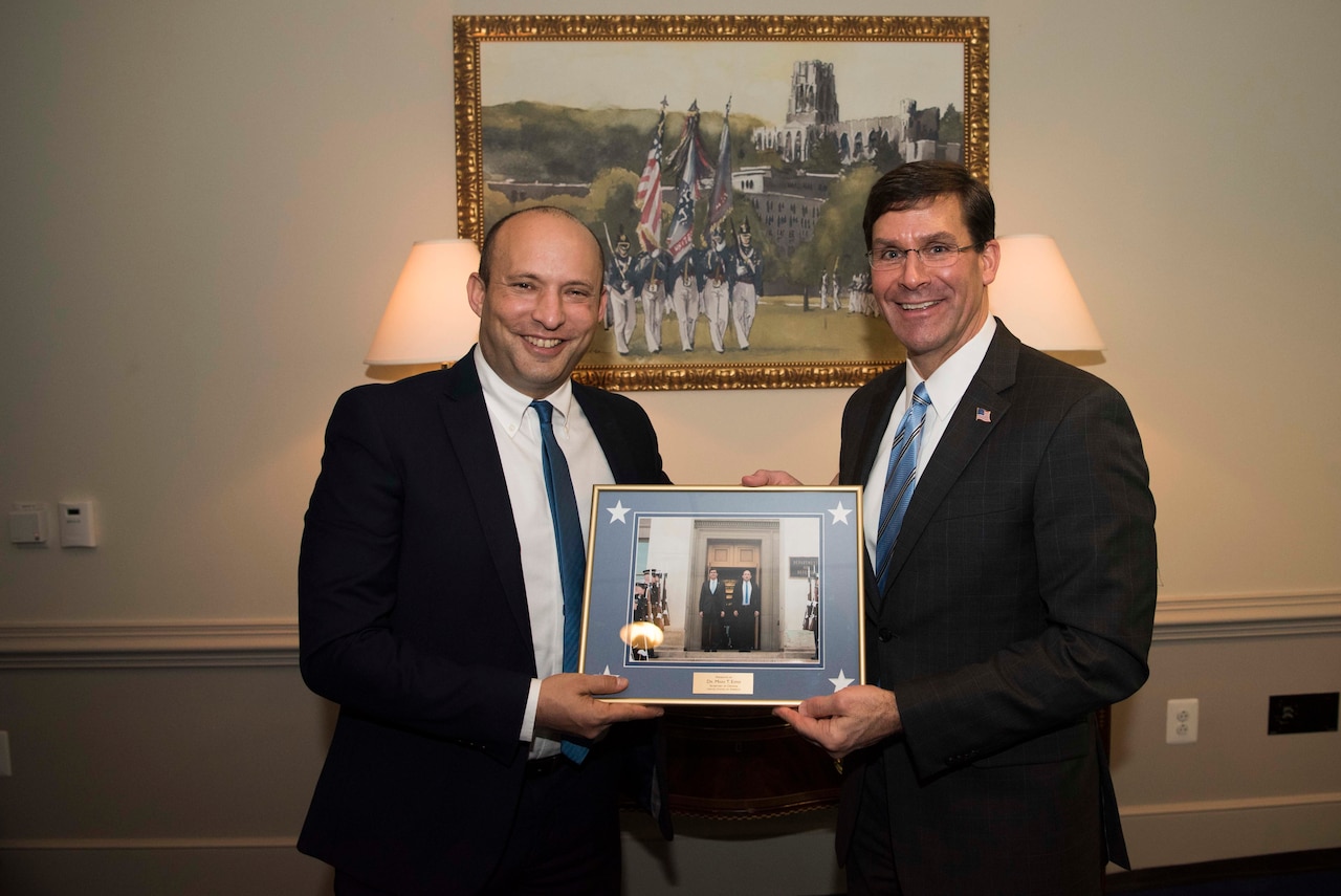 Defense Secretary Dr. Mark T. Esper and another civilian hold a framed picture and smile at the camera.