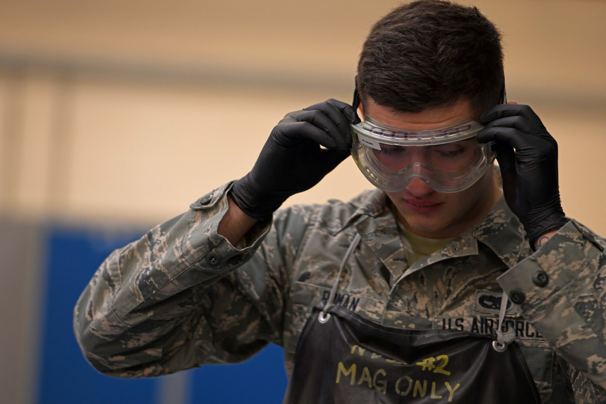 Airman 1st Class Camden Roman, 100th Maintenance Squadron non-destructive inspection journeyman, adjusts his safety equipment at RAF Mildenhall, England, Jan. 23, 2020. Protective eyewear is used to keep the eyes safe from the florescent penetrant chemicals the non-destructive inspection shop uses to find tiny cracks to in parts. (U.S. Air Force photo by Staff Sgt. Lexie West)