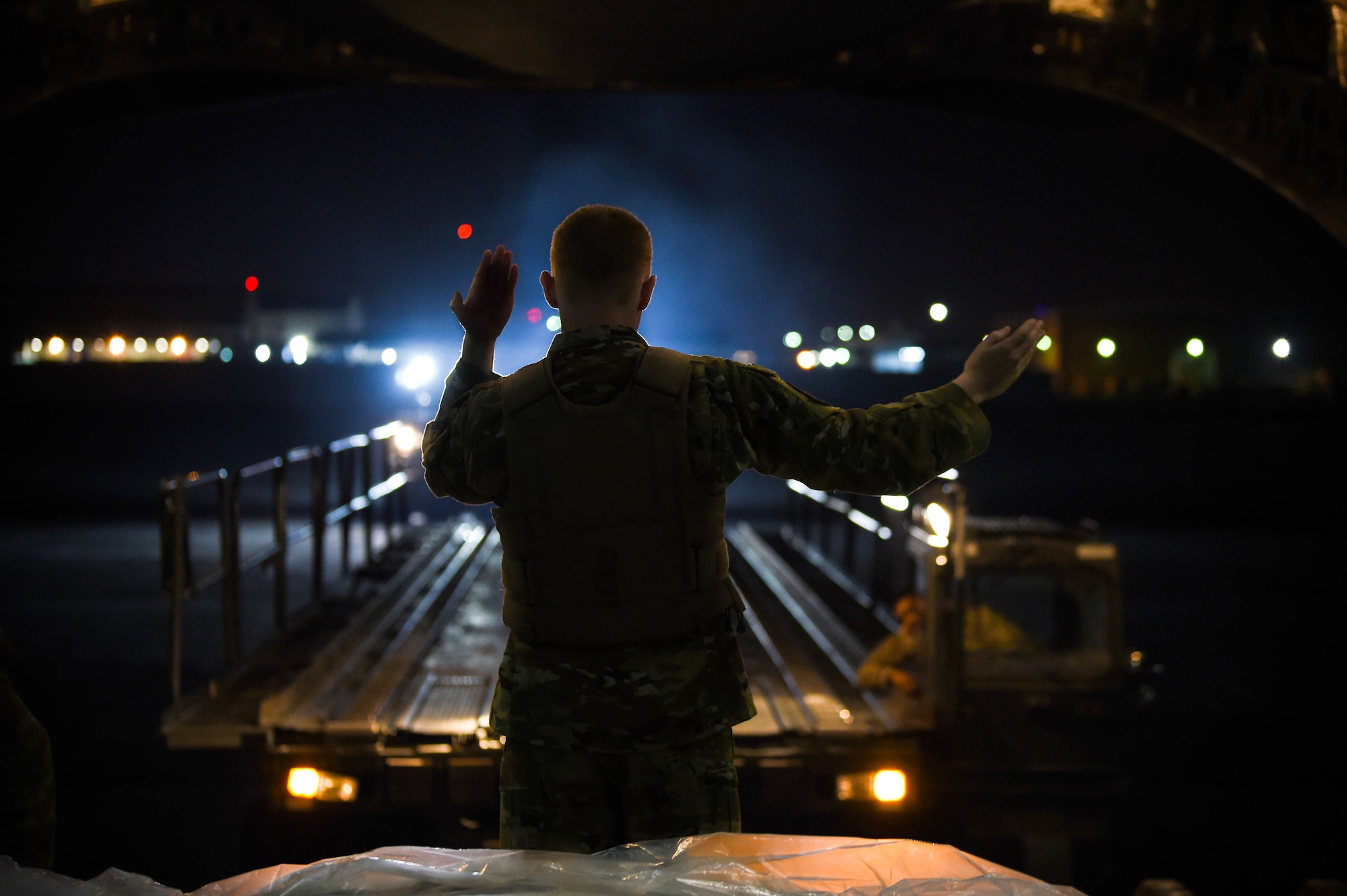 Airman 1st Class Kam Watt, 4th Airlft Squadron loadmaster, marshalls a K-loader up to the back of a C-17 Globemaster III to offload cargo in Iraq, Dec. 20, 2019. A C-17 loadmaster is responsible for the on-load and off-load of cargo from the aircraft, and for securing it while in transit. (U.S. Air Force photo by Airman 1st Class Mikayla Heineck)