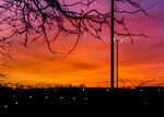 Sun sets behind buildings.