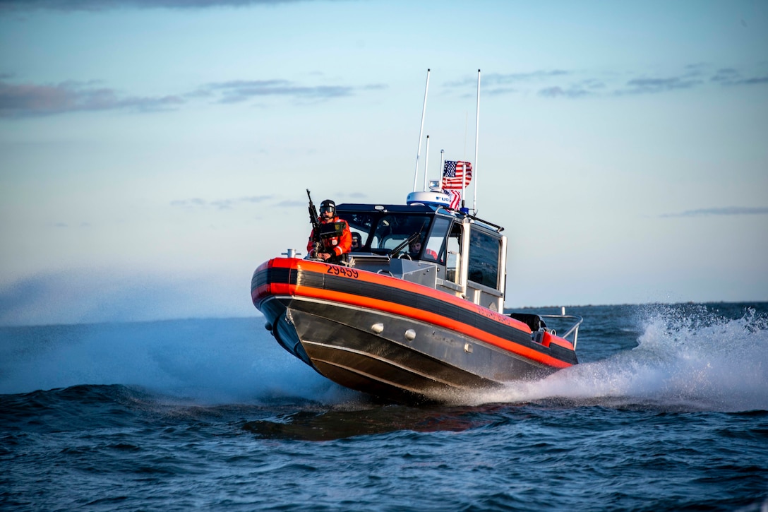 A Coast Guardsman rides in a small boat.