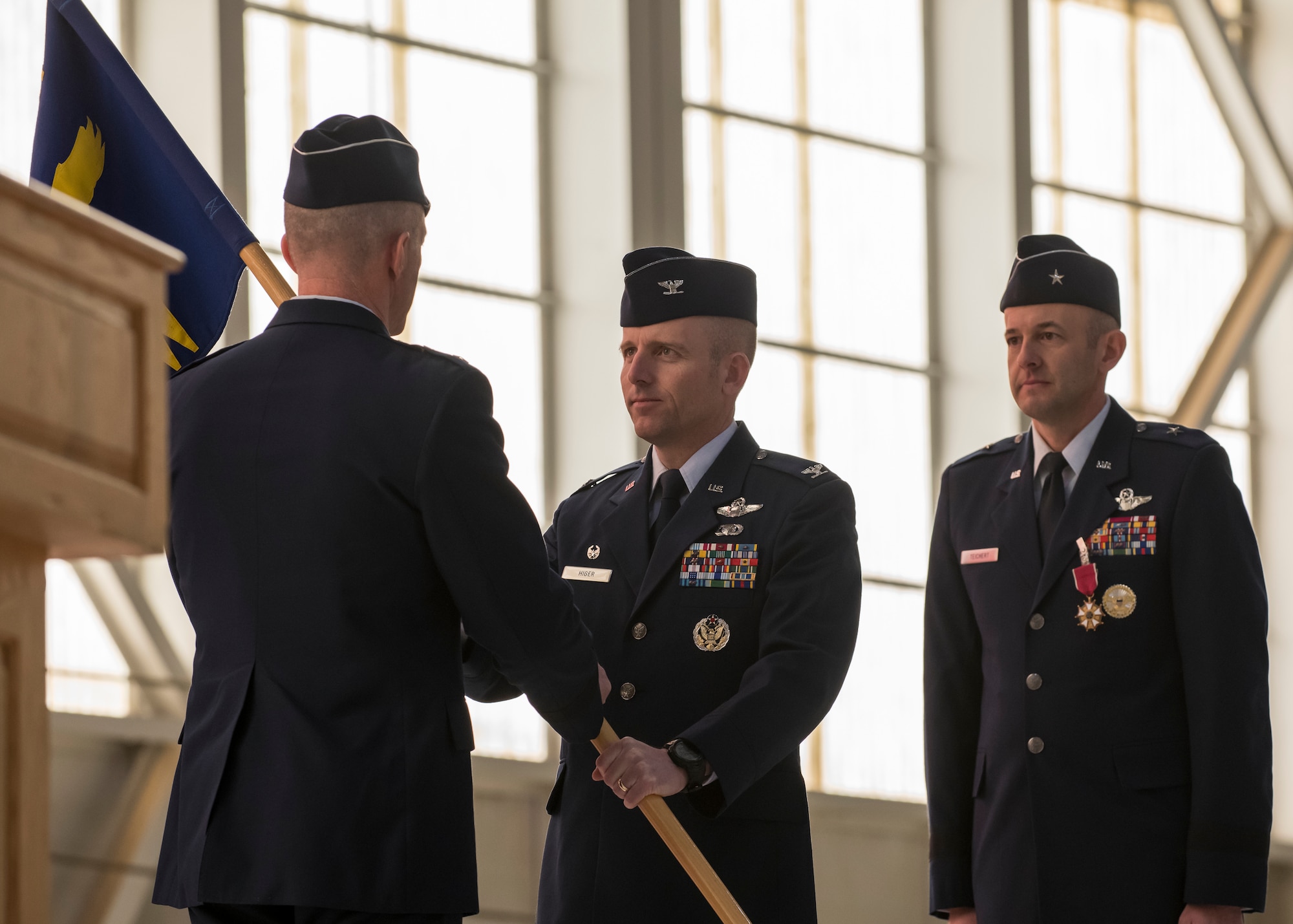 The 412th Test Wing’s new commander, Col. Matthew Higer, assumes command of the Wing by receiving the unit guidon from Maj. Gen. Christopher Azzano, Air Force Test Center Commander, during the Wing’s Change of Command Ceremony at Edwards Air Force Base, California, Feb. 5. (Air Force photo by Giancarlo Casem)