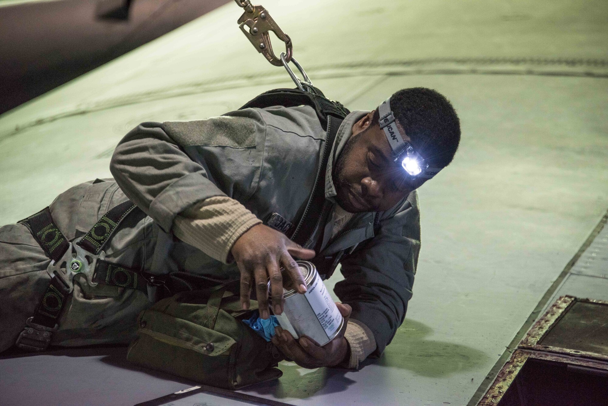 U.S. Air Force Master Sgt. Eugene Jackson of the 166th Maintenance Squadron fuel systems maintenance shop, Delaware Air National Guard, prepares to reseal a leaky fuel system access door on top of the right wing of a C-130H2 aircraft. Because fuel system maintainers have to work in high places, they are required to clip into a safety harness. (Courtesy Photo)