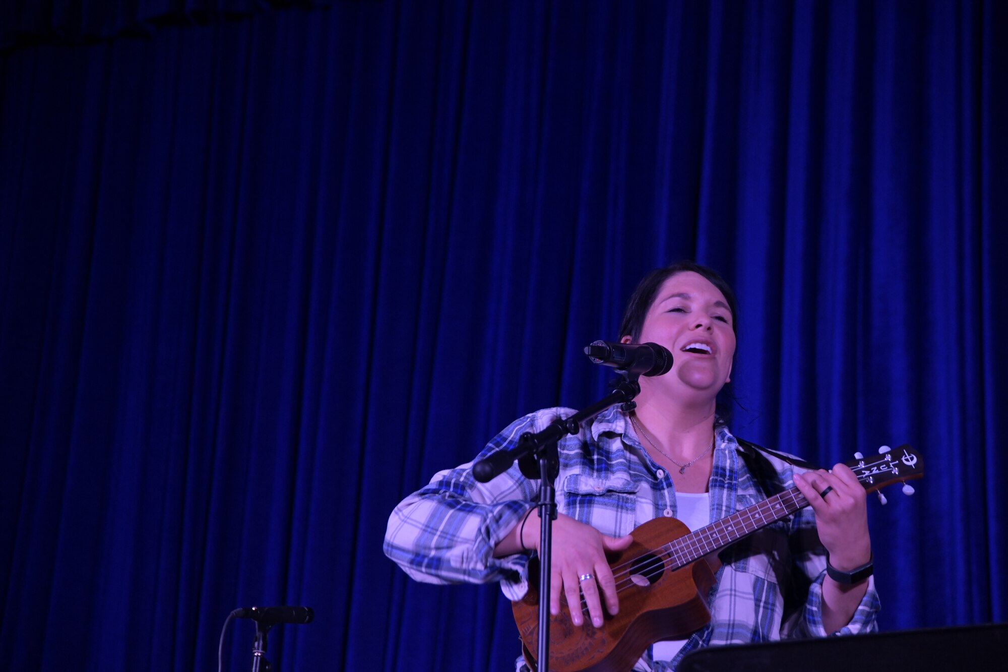 Tech. Sgt. Amy Chicavich, Air Forces Central Command Band member, play the ukulele and sings as part of her performance in The Rock theater at Ali Al Salem Air Base, Kuwait January 3, 2020. The AFCENT Band is comprised of Airmen that have been selected by musical proficiency and then travel communicating to deployed members and local communities through music. (U.S. Air Force photo by Tech. Sgt. Alexandre Montes)