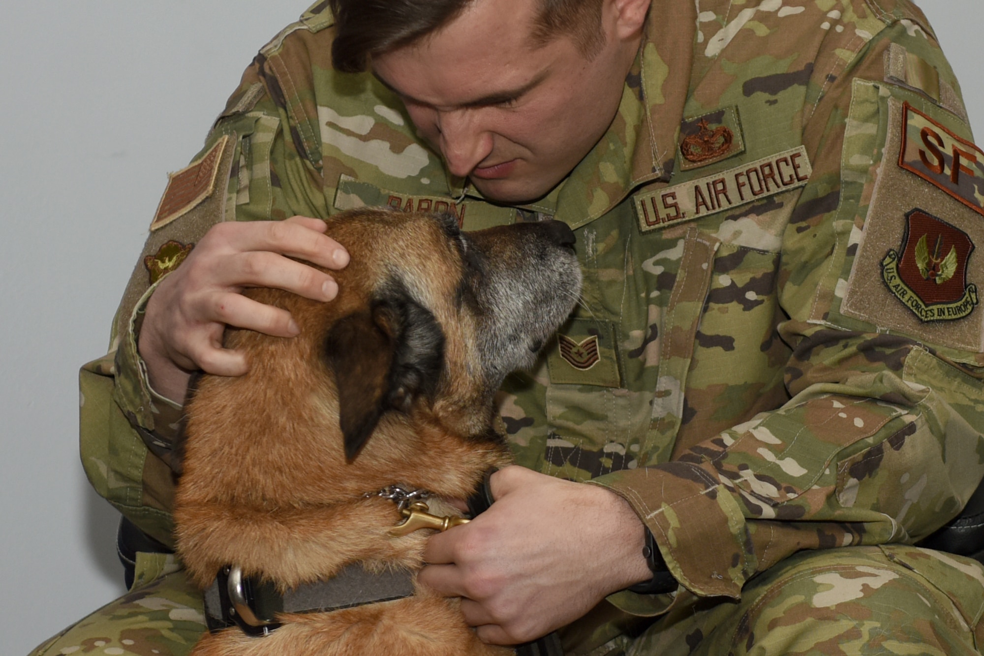 Tech. Sgt. Alexander Baron, a 48th Security Forces Squadron military working dog handler, shows some love to his K9 companion, YYogi, a 48th SFS MWD, during the dog’s retirement ceremony at Royal Air Force Lakenheath, England, Jan 30, 2020. During his service, YYogi completed over 20 survival, evasion, resistance and escape opposing forces exercises helping over 400 Aircrew earn their Code of Conduct Continuation Training making sure they were combat mission ready. (U.S Air Force photo by Airman 1st Class Jessi Monte)