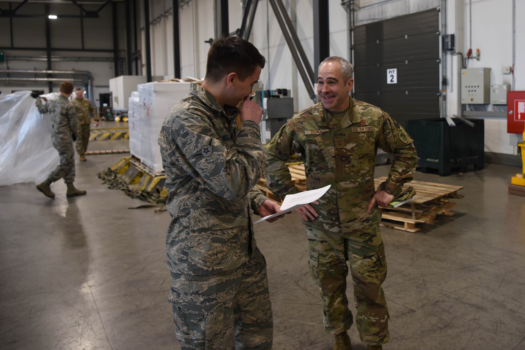 Chief Master Sgt. Kristopher Berg, Air Force Expeditionary Center command chief, speaks with Airman Mark Oglesby, 721st Aerial Port Squadron ramp service specialist during a 521st Air Mobility Operations Wing visit on Ramstein Air Base, Germany, Jan. 29, 2020. The USAF Expeditionary Center provides direct oversight for the global en-route system, building partnership capacity mission sets within the global mobility enterprise, as well as installation support for three joint bases.