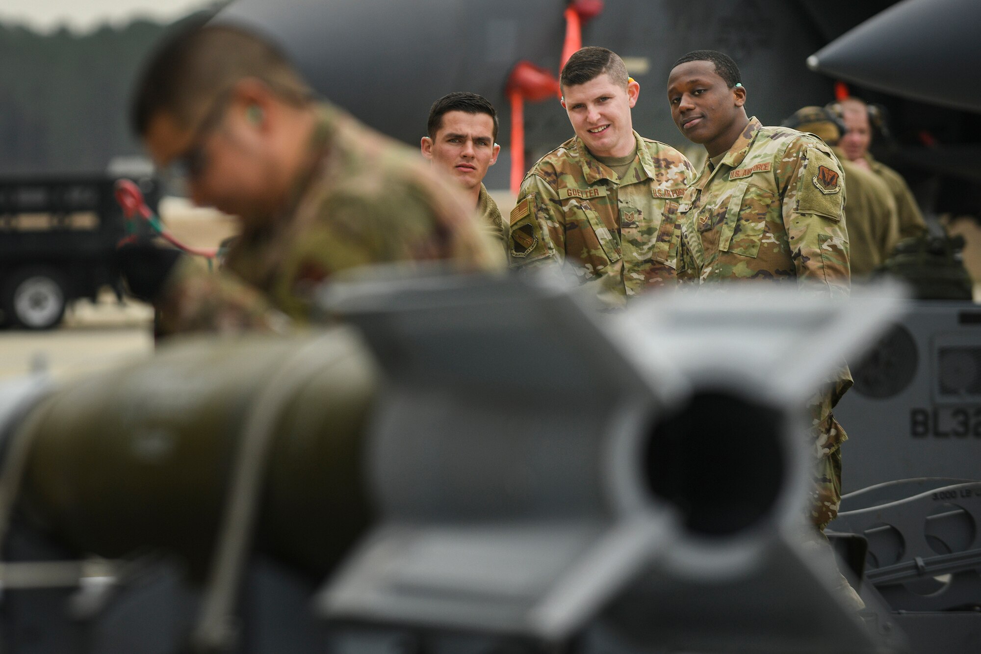 Airmen participanting in the Load Crew Competition of the Quarter, stare as an Airmen on an opposing team loads bombs, Jan. 24, 2020, Seymour Johnson Air Force Base, N.C.