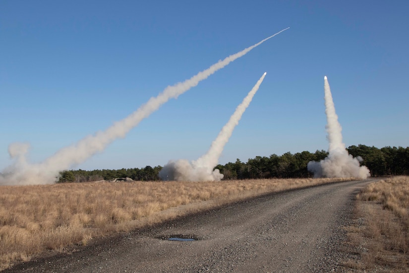 Three rockets fired into the sky leave smoke trails behind them.