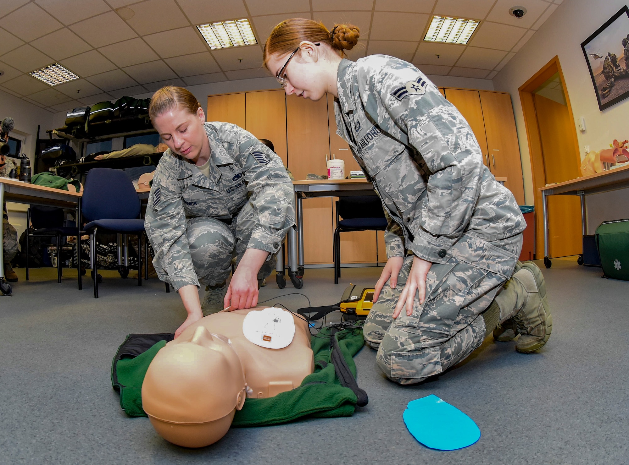 U.S. Air Force Tech. Sgt. Bethany Sonnick, left, 86th Medical Group education and training program coordinator, instructs Airman 1st Class Brittany Wey, 21st Operational Weather Squadron forecaster, apply automated external defibrillator pads during an adult cardiopulmonary resuscitation and AED class at Ramstein Air Base, Germany, Feb. 4, 2020.  Sonnick demonstrated techniques to the class and required each student to demonstrate the techniques on mannequins. To pass the class, each student had to respond to a mock scenario and demonstrate understanding of life-saving techniques. Personnel who learn to operate an AED and perform CPR can provide a safer work environment to support Ramstein’s airlift mission.